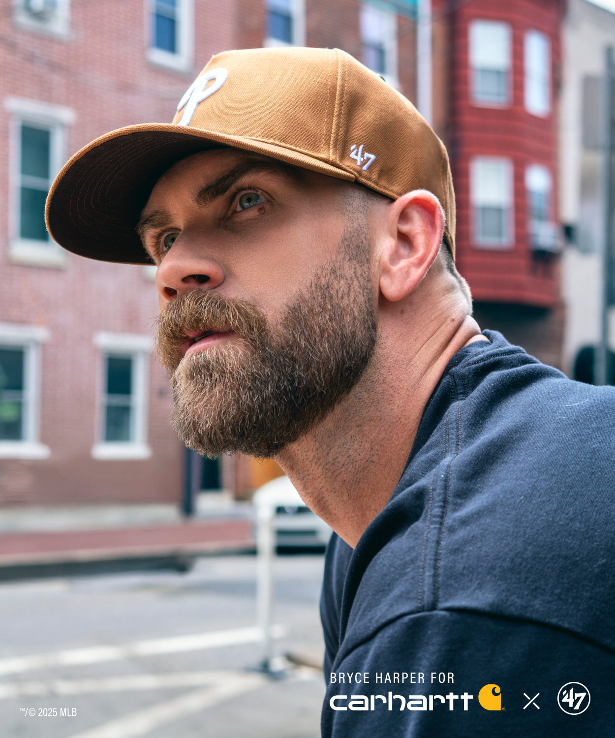 Bryce Harper wearing a brown cap with a visible '47 brand logo, standing on a street.BRYCE HARPER FOR CARHARTT X 47